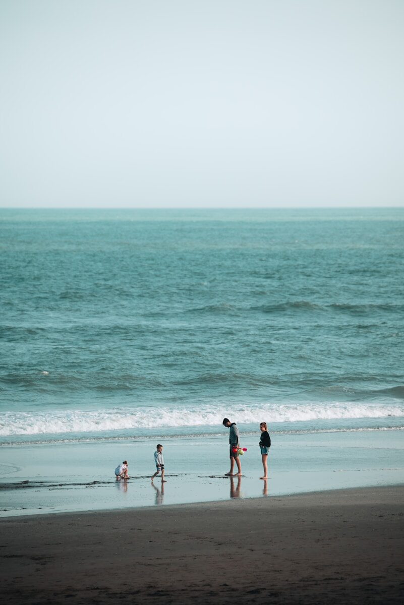 a group of people walking along a beach next to the ocean