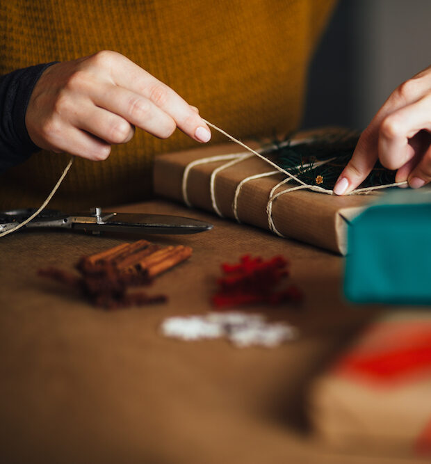 woman wrapping modern christmas gifts presents at home